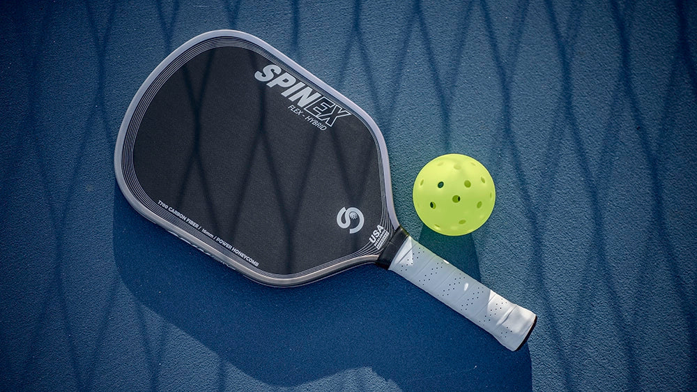 A Spinex FLEX Hybrid T700 carbon pickleball paddle and ball on an Australian blue court