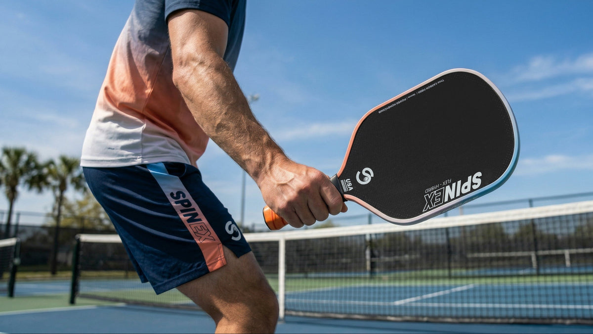 Player mid-swing with a Spinex FLEX Hybrid pickleball paddle under a blue sky