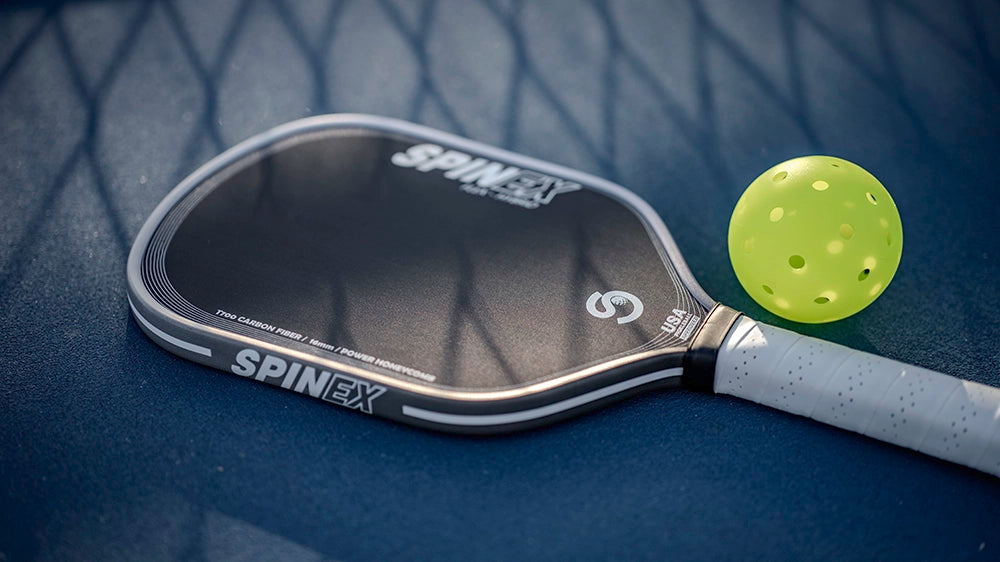 SpinEx pickleball paddle with a ball on a blue surface