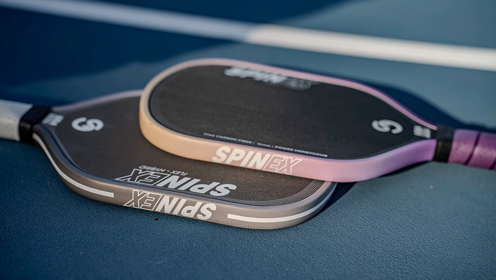 Two pickleball paddles with SpinX branding on a blue surface