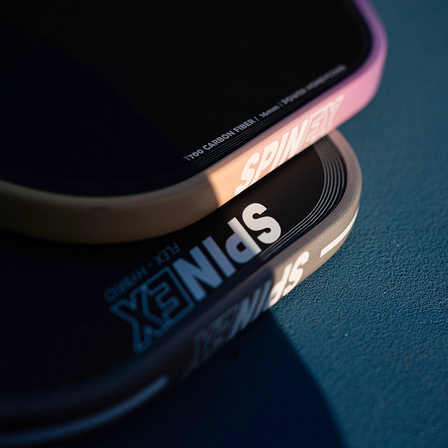 Two Spinex paddles stacked on a blue textured surface