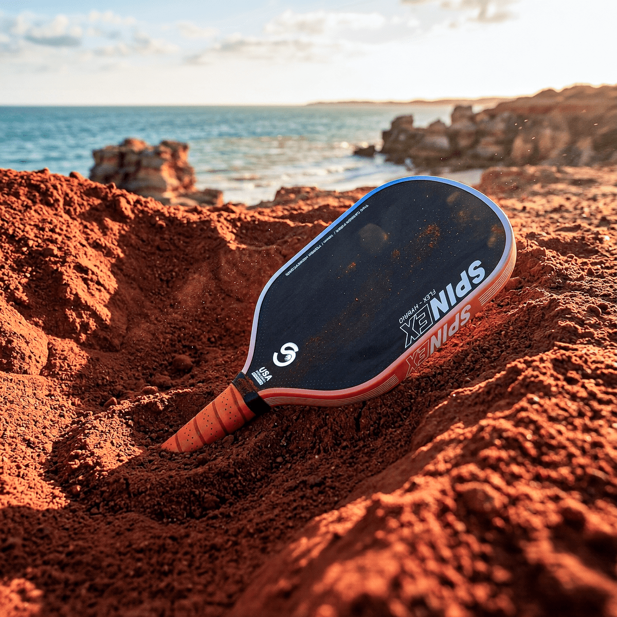 Spinex FLEX Hybrid Broome pickleball paddle resting on the red sand coastline of Broome, Western Australia